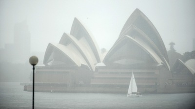Australia Floods: A yacht sails next to the Opera House while it rains in Sydney. (AFP) Australia Floods: A yacht sails next to the Opera House while it rains in Sydney. (AFP)