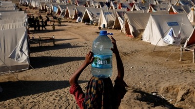Pakistan Floods: A displaced girl carries a bottle of water she filled from nearby stranded flood-waters in Sehwan, Pakistan. (Reuters)