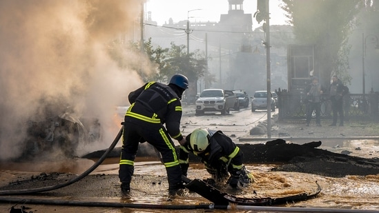 Russia-Ukraine War: A firefighter helps his colleague to escape from a crater as they extinguish smoke from a burned car after a Russian attack in Kyiv, Ukraine.(AP)