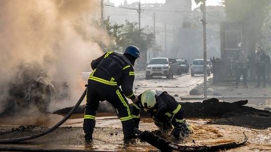 Russia-Ukraine War: A firefighter helps his colleague to escape from a crater as they extinguish smoke from a burned car after a Russian attack in Kyiv, Ukraine.(AP) Russia-Ukraine War: A firefighter helps his colleague to escape from a crater as they extinguish smoke from a burned car after a Russian attack in Kyiv, Ukraine.(AP)