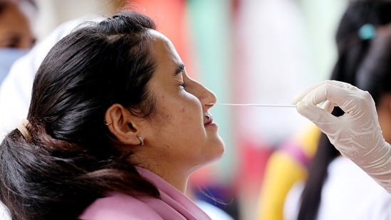 A healthcare worker collects a nasal swab sample of a woman for the Covid-19 testing. (Representational image)(HT Photo)