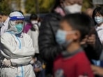 Covid In Beijing: A worker in protective suit stands watch as masked residents wait in line to get their routine in Beijing.