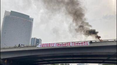 Smoke rises as a banner with a protest message hangs off Sitong Bridge, Beijing, China, on October 13, 2022 (REUTERS) Smoke rises as a banner with a protest message hangs off Sitong Bridge, Beijing, China, on October 13, 2022 (REUTERS)
