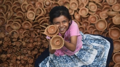 A girl holds diyas in her hands and beams with excitement to welcome the festival of lights. (Deepak Gupta/ HT Photo) 