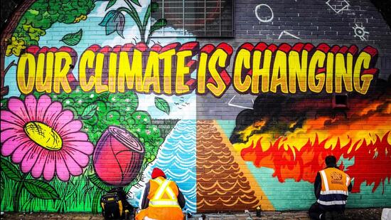 Street artists paint a mural on a wall opposite the COP26 climate summit venue in Glasgow on October 13, 2021. (AFP)