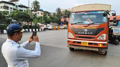 Mumbai, India - October 21, 2022: A traffic police personnel seen taking action and issuing e-challan to a heavy vehicle near Mulund Toll Naka, Mumbai, in Mumbai, India, on Friday, October 21, 2022. (Praful Gangurde/HT Photo) (HT PHOTO)