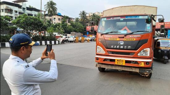 Mumbai, India - October 21, 2022: A traffic police personnel seen taking action and issuing e-challan to a heavy vehicle near Mulund Toll Naka, Mumbai, in Mumbai, India, on Friday, October 21, 2022. (Praful Gangurde/HT Photo) (HT PHOTO)