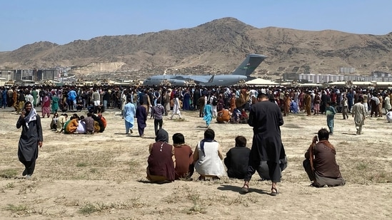 Hundreds of people gather near a U.S. Air Force C-17 transport plane at the perimeter of the international airport in Kabul, Afghanistan, August 16, 2021.(AP)