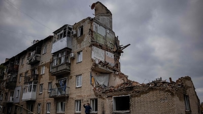 A man takes pictures with a phone beside a damaged building in Lyman, Donetsk region. (AFP) A man takes pictures with a phone beside a damaged building in Lyman, Donetsk region. (AFP)