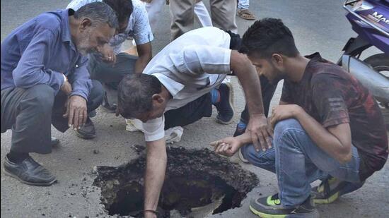An MC team inspecting the road cave-in near Gulati Chowk, Model Town, Ludhiana. (Harvinder Singh/HT)