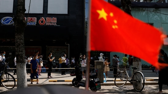 China’s Communist Party: A China's flag flutters near people lining up to get tested at a makeshift nucleic acid testing site. (File image)(Reuters)