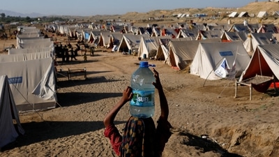 Pakistan Floods: A displaced girl carries a bottle of water she filled from nearby stranded flood-waters, as her family takes refuge in a camp, in Sehwan, Pakistan. (Reuters)