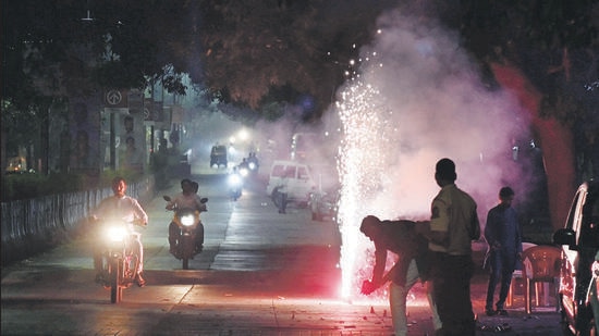 Residents burn firecrackers on the road as vehicles pass by on the occasion of Laxmi Pujan on Pashan Road, on Monday. (HT PHOTO)