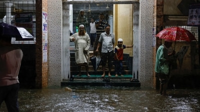 People wait at the gate of a mosque as streets in Dhaka are flooded before cyclone Sitrang hit the country.(REUTERS) 