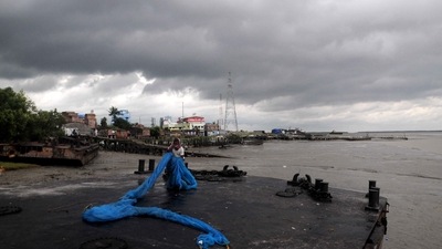 Dark clouds hover in the sky as a fisherman folds his fishing net before the landfall of Cyclone Sitrang, in South 24 Parganas district of West Bengal on Monday. (PTI) Dark clouds hover in the sky as a fisherman folds his fishing net before the landfall of Cyclone Sitrang, in South 24 Parganas district of West Bengal on Monday. (PTI)