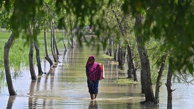 A woman wades through clogged tidal water after cyclone Sitrang hit in West Bengal's Kalapara. (AFP) A woman wades through clogged tidal water after cyclone Sitrang hit in West Bengal's Kalapara. (AFP)