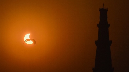 View of partial solar eclipse seen alongside Qutub Minar from New Delhi's Mehrauli. (Raj K Raj/ HT Photo)