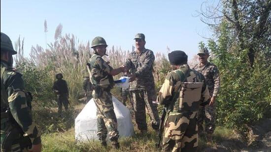 Officers of the BSF and Pak Rangers exchange sweets along international border in Jammu on Diwali. (HT Photo)