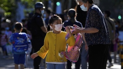 Wuhan Lockdown: A woman wearing a face mask sends a child to a primary school. (AP) Wuhan Lockdown: A woman wearing a face mask sends a child to a primary school. (AP)