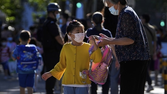 Wuhan Lockdown: A woman wearing a face mask sends a child to a primary school.(AP) Wuhan Lockdown: A woman wearing a face mask sends a child to a primary school.(AP)