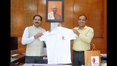 Chandigarh adviser Dharam Pal and (right) Daily World newspaper’s editor-in-chief Manish Tiwari launching the T-shirt for the marathon at UT secretariat on Thursday. (Ravi Kumar/HT)