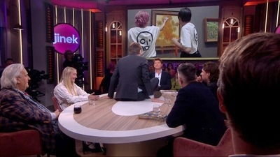 The video shows a man, initially seated as one of the panellists in the show called ‘Jinek’, taking the glue out of his pocket, climbing on the table and sticking himself on top. (Twitter/@Jelle_De_Graaf)