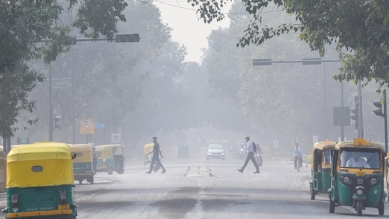 Commuters crossing a road as a layer of smog covers Kartavya Path in the morning, in New Delhi on Friday. (ANI Photo)