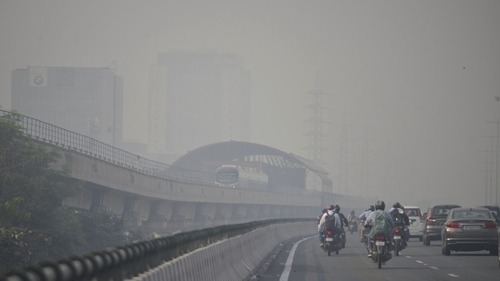 Vehicles and a metro train run on the Delhi-Gurugram Expressway on a smoggy day, in Gurugram on Friday. (ANI Photo)