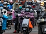 Covid In China: Commuters wearing face masks ride scooters along a street in the central business district in Beijing.