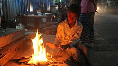 A child sits near a bonfire as mercury dips in Pune. (Ravindra Joshi/HT PHOTO)