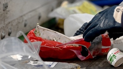 Employee of the Siredom integrated waste treatment centre sorts household waste as it goes through a sorting chain, in a Paris suburb. (AFP)
