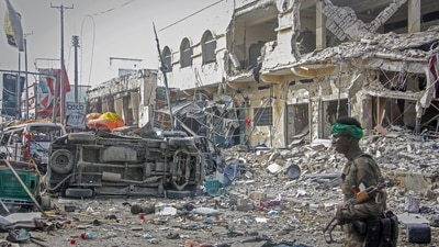 A Somali soldier walks through the scene of a double car-bomb attack in Mogadishu, Somalia, Saturday. (AP)