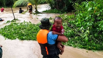 Rescuers help residents evacuate in Kalamansig, Sultan Kudarat on October 28, 2022, due to heavy rains resulting in floodings brought by Tropical Storm Nalgae. (AFP) Rescuers help residents evacuate in Kalamansig, Sultan Kudarat on October 28, 2022, due to heavy rains resulting in floodings brought by Tropical Storm Nalgae. (AFP)