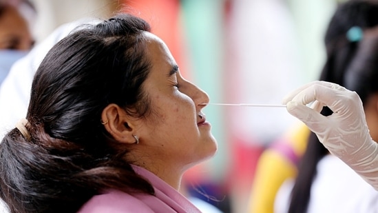 A healthcare worker collects a nasal swab sample of a woman for the Covid-19 testing, amid a recent surge in the Coronavirus cases, in Jammu.(HT Photo)