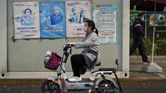 Covid In China: A woman rides past a coronavirus testing facility in Beijing. (AP)