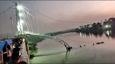 The collapsed portion of an old suspension bridge over the Machchhu river in Morbi district on Sunday. (PTI) The collapsed portion of an old suspension bridge over the Machchhu river in Morbi district on Sunday. (PTI)
