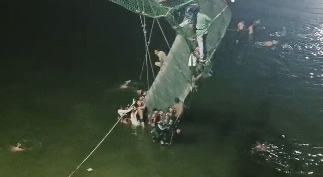 Rescue operation underway after a cable bridge collapsed on the Machchhu river, in Morbi on Sunday. (ANI Photo)