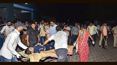 Local residents help shift an injured person to GMERS General Hospital in Morbi district on Sunday. (PTI)