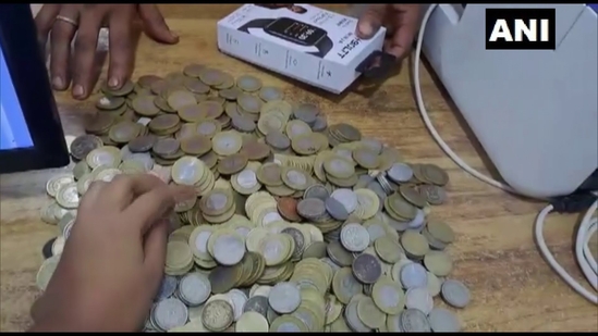 The image shows the showroom employees counting coins paid by a man as down payment for a two-wheeler.(Twitter/@ANI)