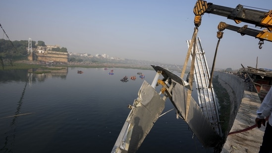 Workers use machinery to remove the bridge that collapsed in Gujarat's Morbi town. (AP)