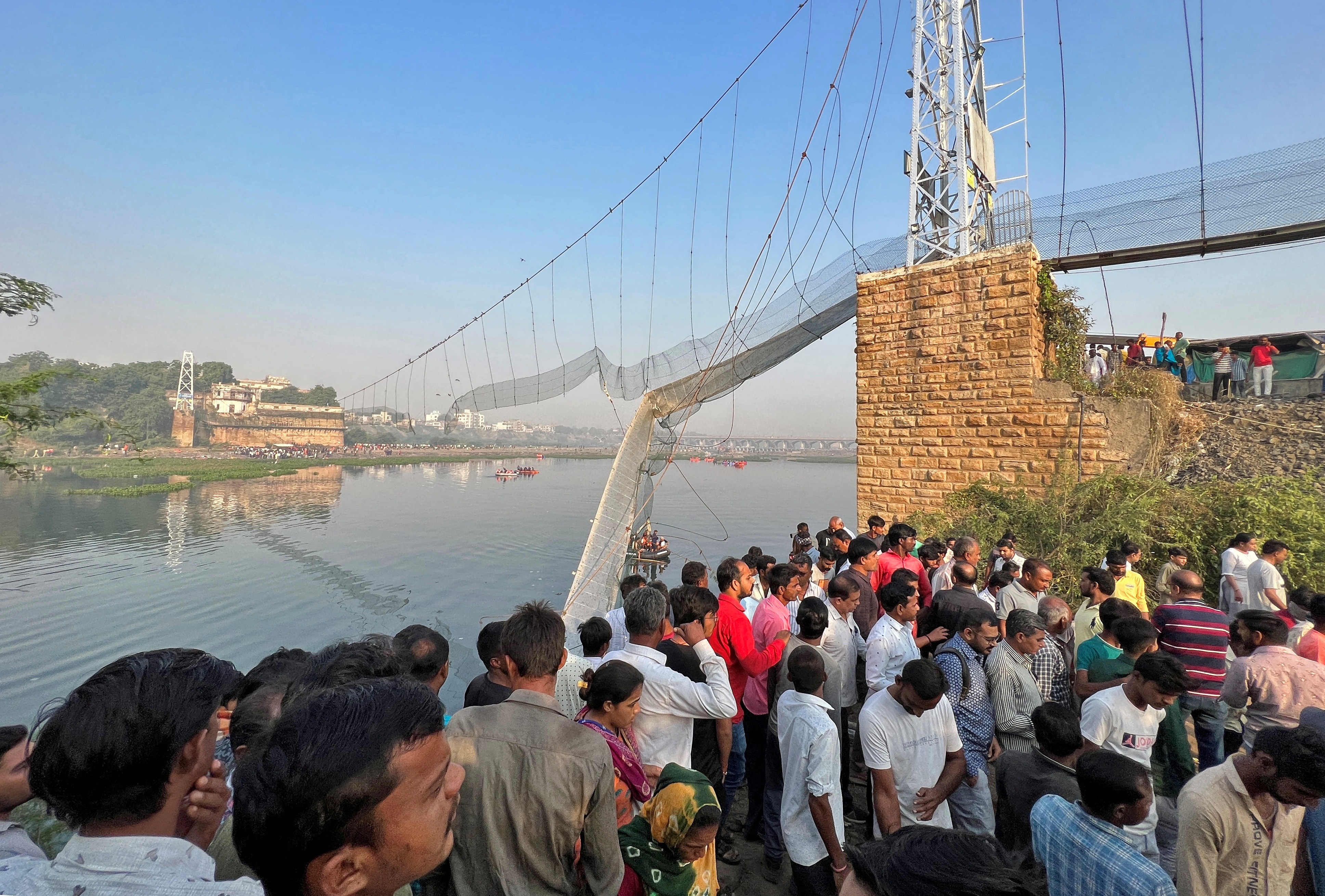 People gather as rescuers search for survivors after a suspension bridge collapsed in Morbi town. (REUTERS)