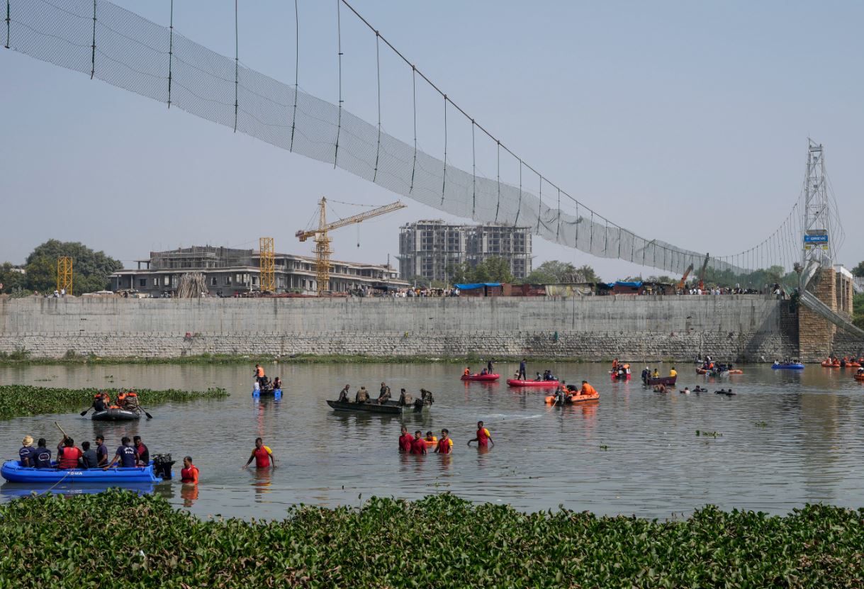 Rescuers on boats search in the Machchu river next to a pedestrian cable bridge that collapsed in Morbi town of western state Gujarat, India, Monday, October 31, 2022. (AP Photo/Ajit Solanki)