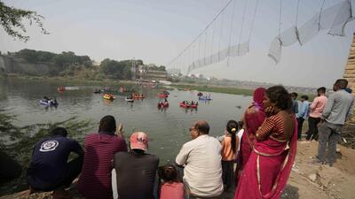 People watch rescuers on boats in the Machchu river. (AP) People watch rescuers on boats in the Machchu river. (AP)