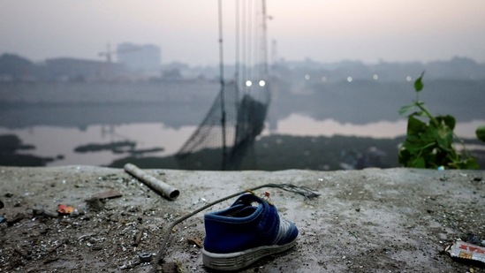 A shoe lies near a damaged suspension bridge after it collapsed on Sunday, in Morbi town. (REUTERS)