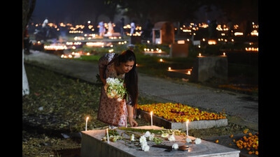A woman lights candles at a grave at Nishatganj paper mill cemetery. (Deeapk gupta/ht photo)