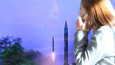 North Korea Missile Launch: A woman walks past a TV screen broadcasting a news report on North Korea firing a ballistic missile. (Reuters)