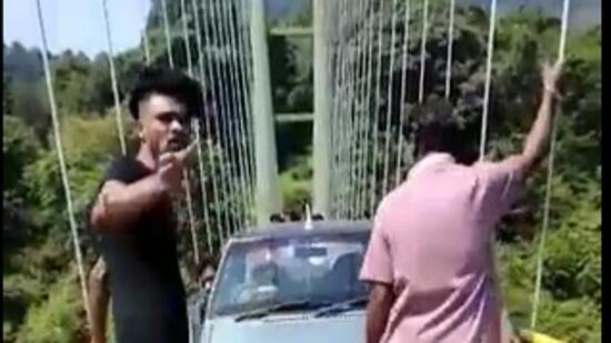 The video, which HT has seen, shows the driver struggling to cross the narrow suspension bridge meant for pedestrians as two men push the car towards the exit. (HT Photo)