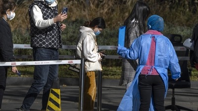 Covid In China: People wearing face masks scan a QR code to register as they line up for COVID-19 tests. (AP)