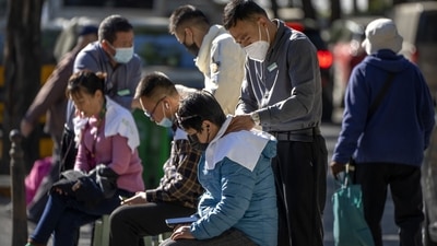 Covid In China: Workers wearing face masks give massages to customers as they sit on chairs on a sidewalk in Beijing. (AP)