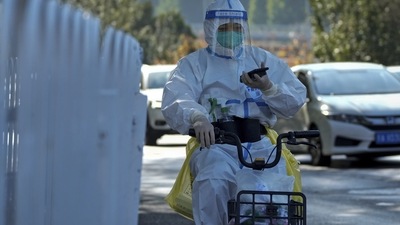 Covid In China: A worker in protective suit rides a bicycle. (AP) Covid In China: A worker in protective suit rides a bicycle. (AP)
